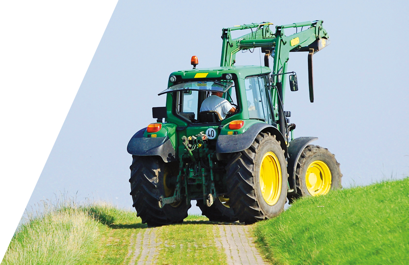 Traktor fährt mit einer Rückfahrkamera über eine Weide mit einem asphaltierten Weg