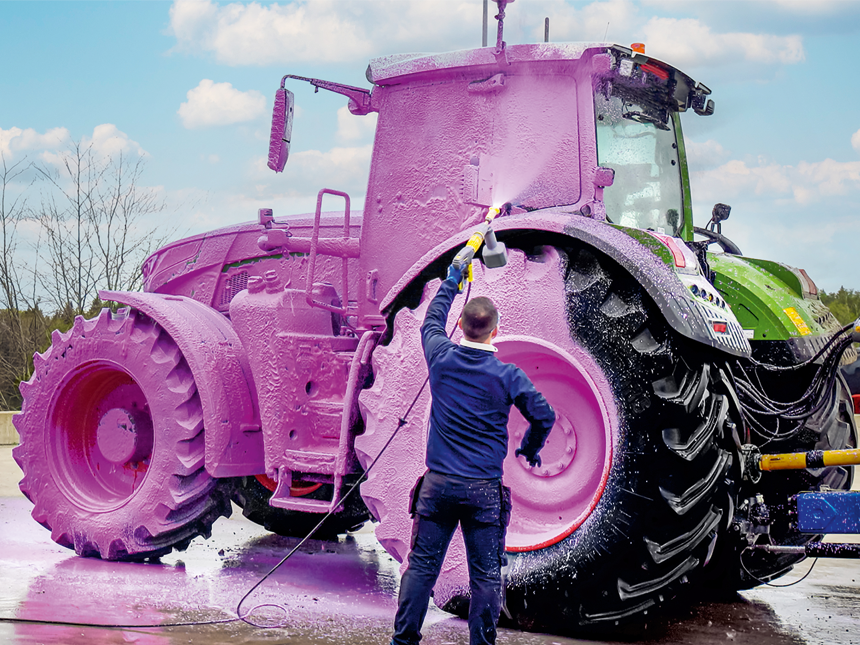 Un homme se tient devant un tracteur recouvert de mousse rose.