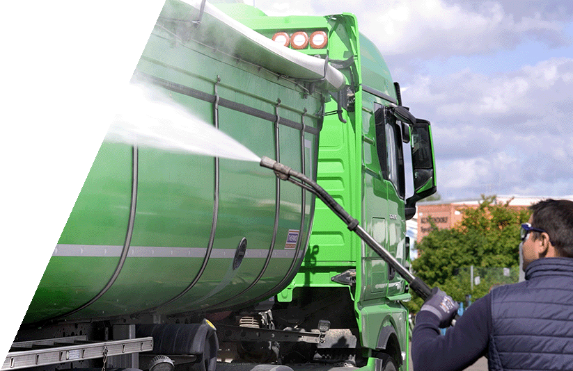 Grünes Nutzfahrzeug, welches von einem Mann mit einem Druckreiniger gereingt wird