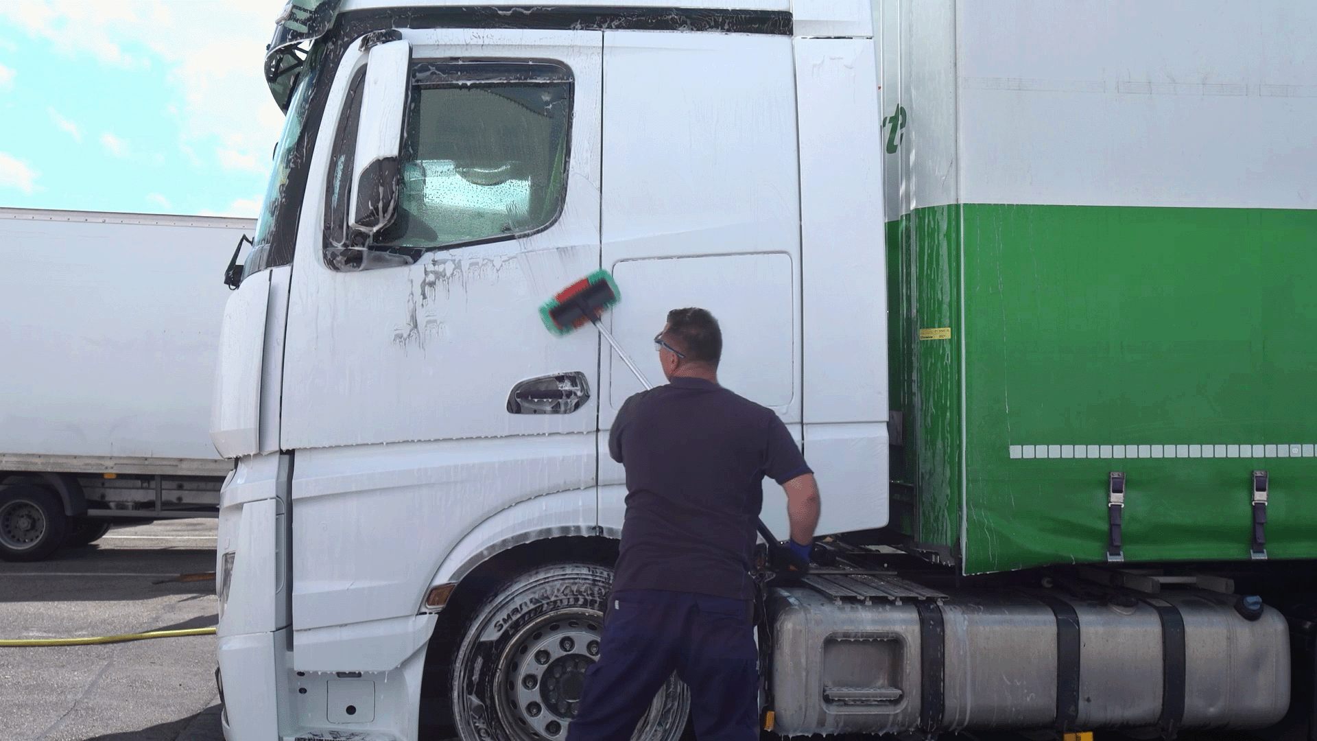 winkler Mitarbeiter reinigt Lkw mit Bürste